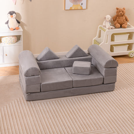 A gray modular kids play couch made of suede fabric, with multiple sections arranged on the floor, suitable for climbing and play activities.