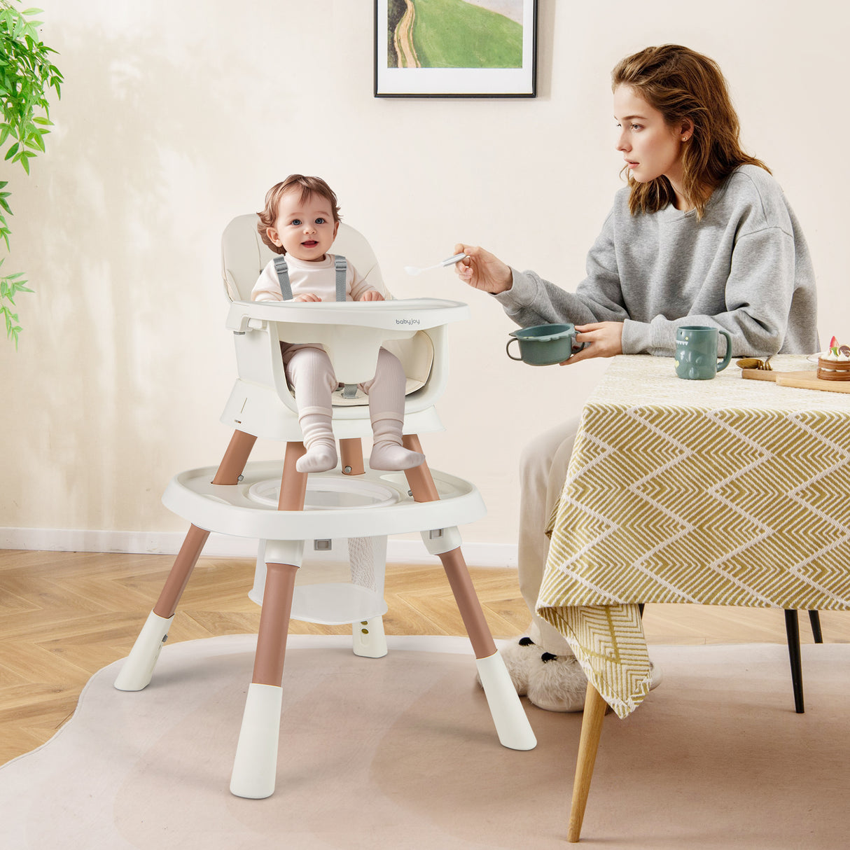 Woman feeding a child in a high chair at a dining table.