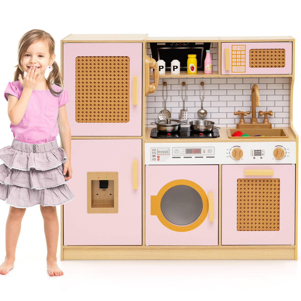 Child next to a pink toy kitchen set with various appliances.