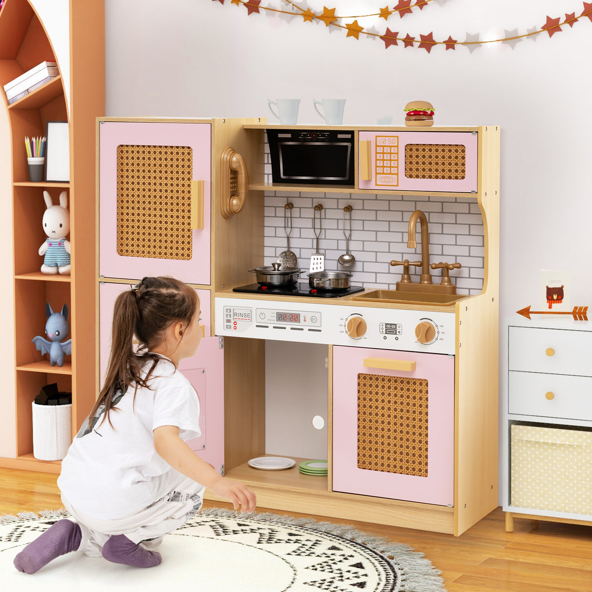 Child playing with a wooden play kitchen set in a room with shelves and decorations.