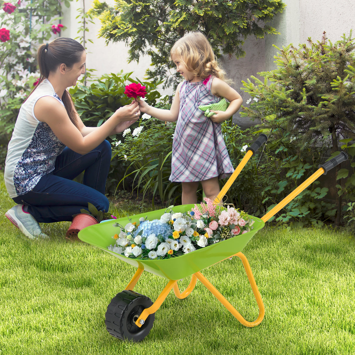 Woman and child with a wheelbarrow full of flowers in a garden setting