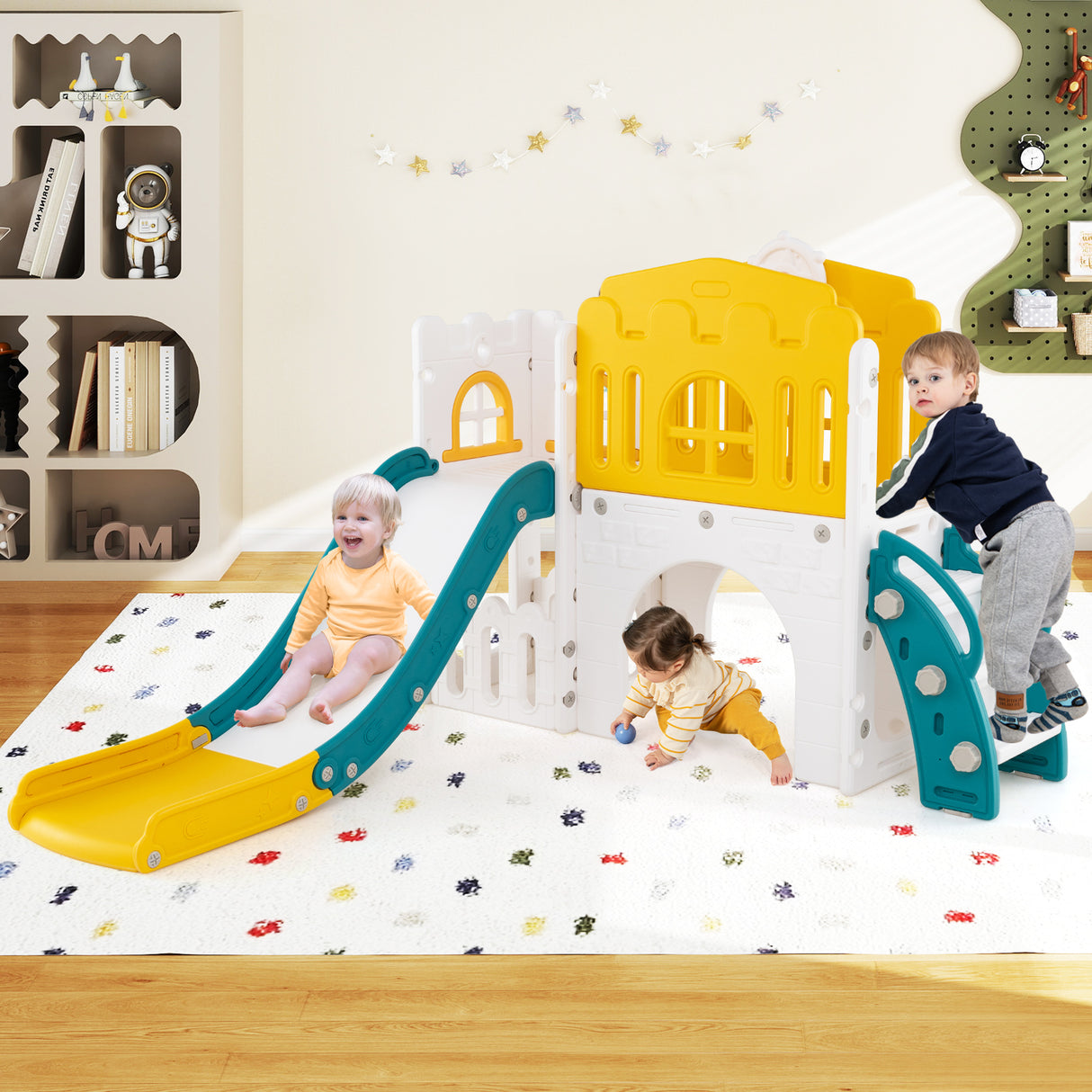 Children playing on a colorful play structure with a slide in a room.