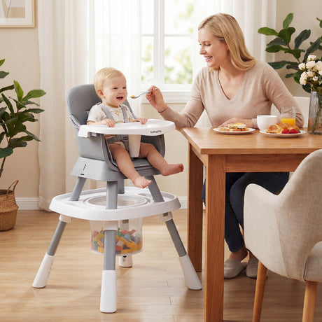 Woman and child using a high chair at a dining table in a bright room.