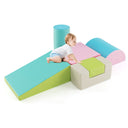 A set of colorful foam play blocks arranged on the floor with a toddler lying on top of a pink wedge block.
