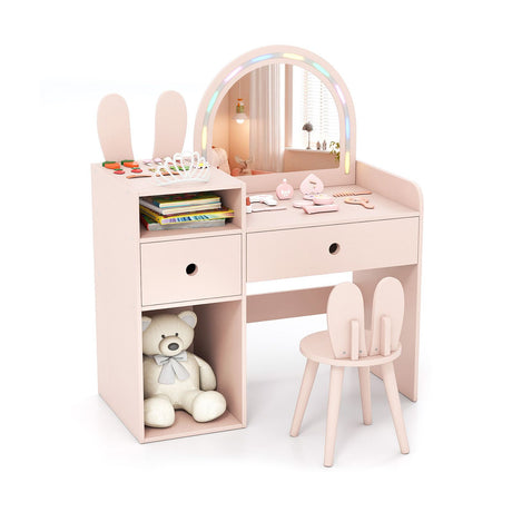 Pink children's vanity table with mirror, chair, and toys on a white background