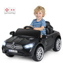 Child sitting in a toy Mercedes-Benz car with a remote control on a white background