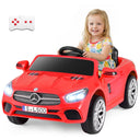 Child sitting in a red toy car with a remote control on a white background