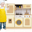 Child in a yellow apron standing next to a toy kitchen set with various appliances.