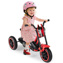 Child riding a red and black tricycle with a helmet on a white background