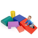 A set of colorful foam play blocks arranged on the floor with a toddler lying on top of a pink wedge block.