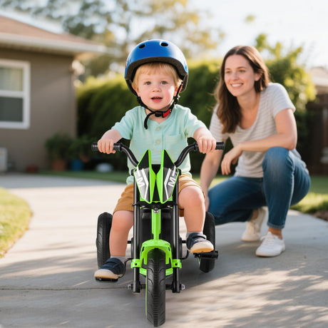 Child riding a green bike with a woman watching in a driveway.
