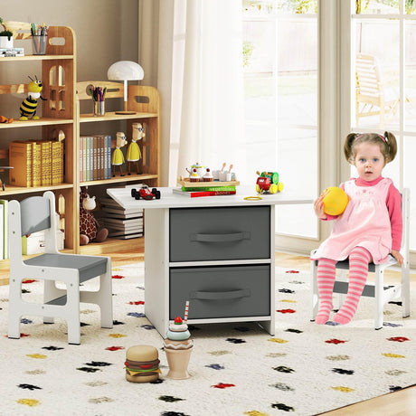 Child in a playroom with a desk, chairs, and toys on a colorful rug.