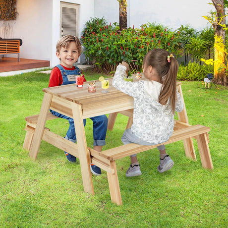 Two children sitting at a wooden outdoor table in a garden.